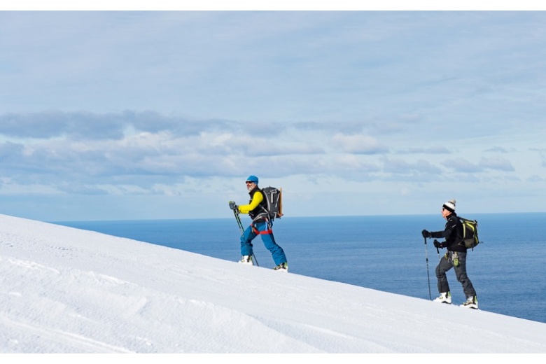 skieurs qui montent à skis avec océan antarctic au fond